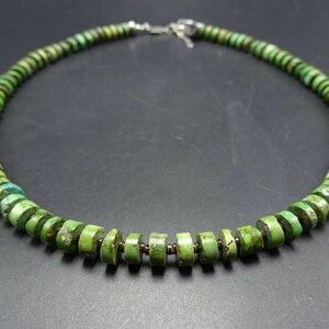 May include: A green turquoise bead necklace with a silver clasp. The beads are round and have a slightly irregular shape.