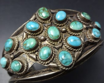 May include: A silver bracelet with a geometric design and turquoise stones. The bracelet is made of sterling silver and features a unique pattern of turquoise stones.