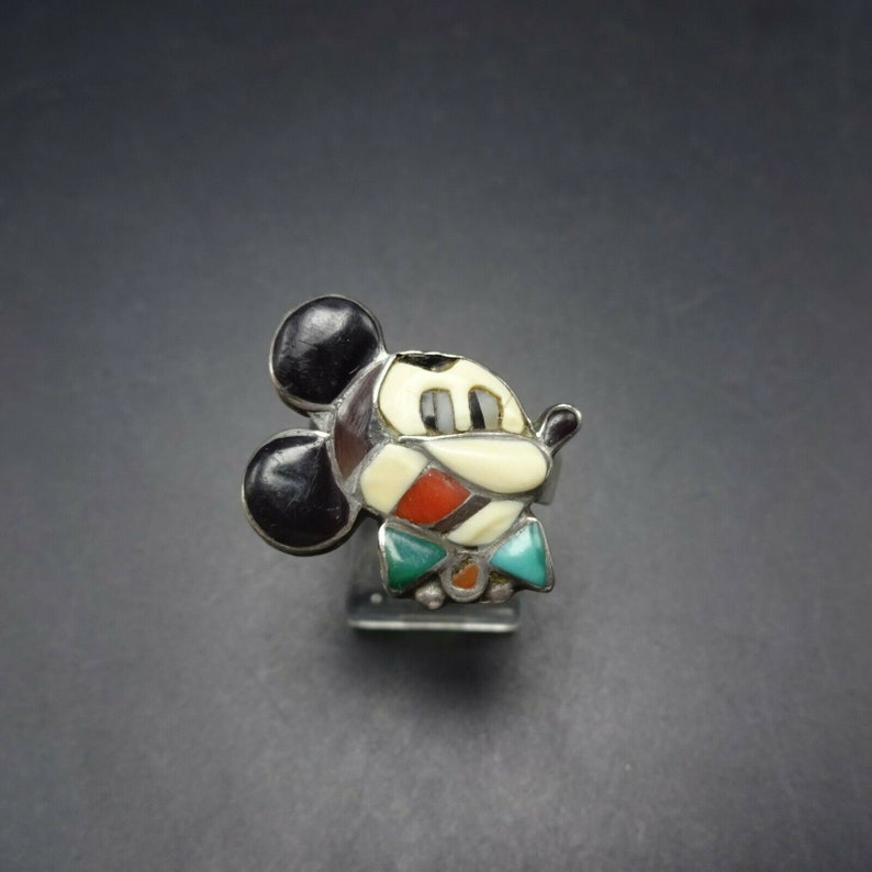 May include: A silver ring with a Mickey Mouse design made of inlaid turquoise, coral, and other stones.
