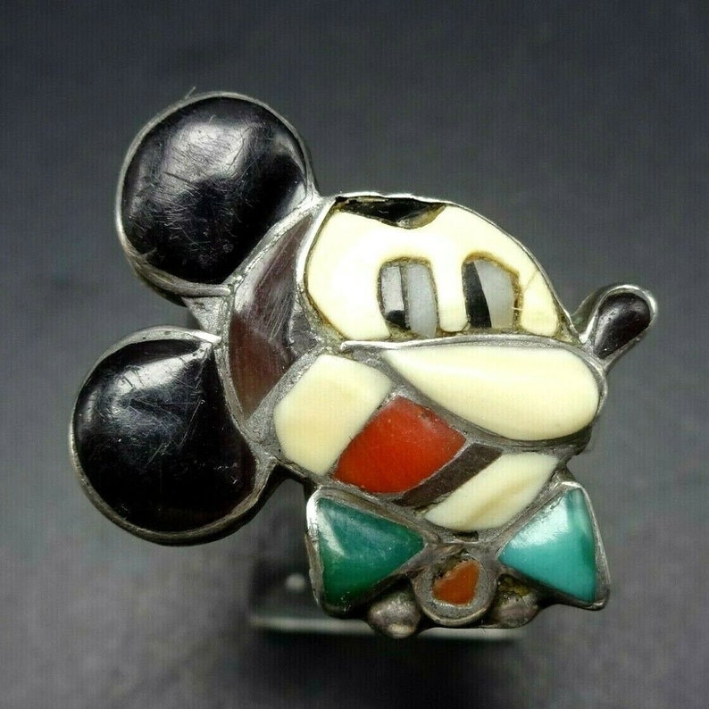 May include: A silver ring with a mosaic Mickey Mouse design. The mosaic is made of various stones, including black, white, red, and turquoise.