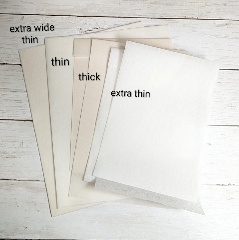 以下が含まれることがあります： 「extra wide thin」、「thin」、「thick」、「extra thin」とラベルされた、さまざまな厚さの紙サンプル。オフホワイトからクリーム色まで、明るい木目調の背景に配置されています。