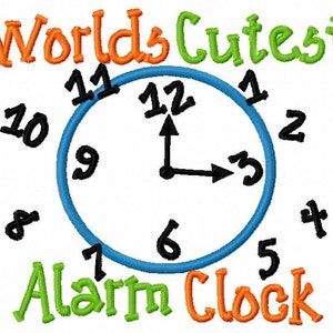 May include: A blue and white clock with the words "World's Cutest Alarm Clock" in orange and green. The clock face has black numbers and hands.