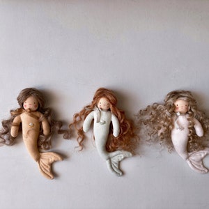 May include: Three handmade fabric mermaid dolls with curly hair. The dolls are wearing different colored outfits: brown, light green, and pink.