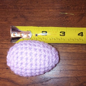 May include: A light purple crocheted egg measuring approximately 3 inches in diameter.