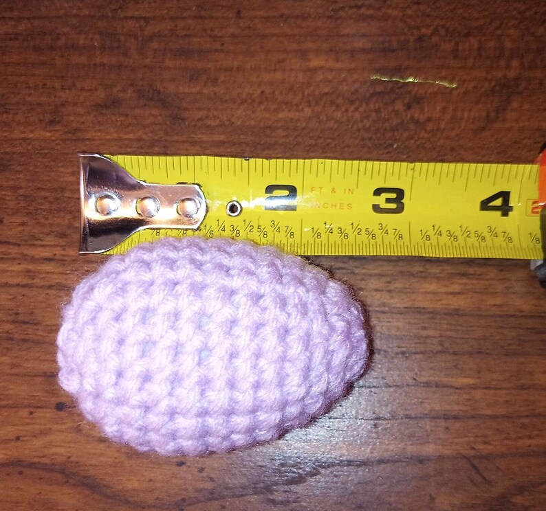 May include: A light purple crocheted egg measuring approximately 3 inches in diameter.