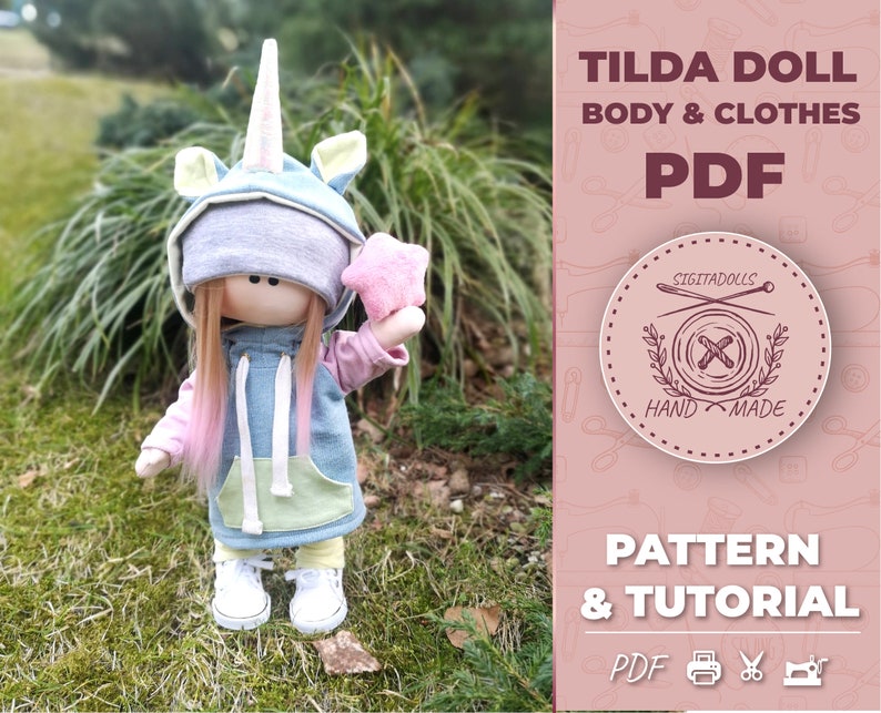 May include: A PDF pattern and tutorial for making a Tilda doll with a unicorn-themed outfit. The doll is wearing a blue hooded sweatshirt with a yellow pocket, pink sleeves, and a unicorn horn and ears. The doll is holding a pink star. The text "TILDA DOLL BODY & CLOTHES PDF" and "PATTERN & TUTORIAL PDF" is visible in the image.