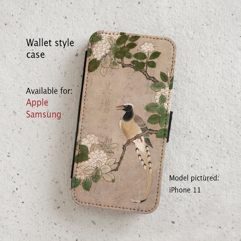 May include: A wallet style phone case with a beige background featuring a stylized illustration of a bird perched on a branch with white flowers. The text "其構思" is visible in the background.