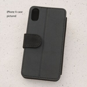 May include: Black leather iPhone X case with a flap that folds over the screen. The case has a textured surface and a small flap with a snap closure.