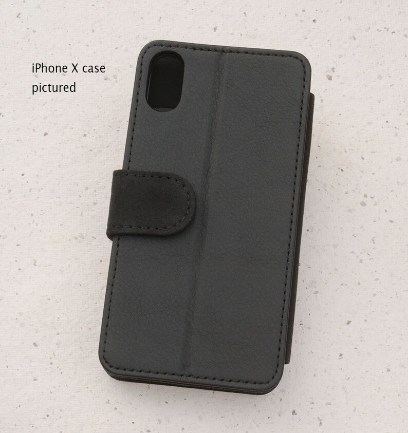 May include: Black leather iPhone X case with a flap that folds over the screen. The case has a textured surface and a small flap with a snap closure.