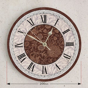 May include: A brown and white round wall clock with Roman numeral markings and a floral design. The clock is 8 inches in diameter.