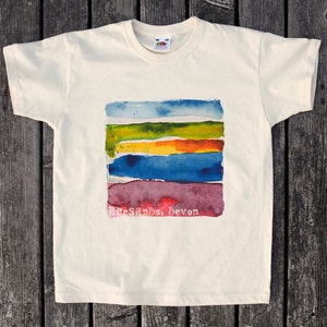 May include: A white t-shirt featuring a watercolour design of horizontal stripes in shades of blue, green, yellow, orange, and purple. The text "Beesands, Devon" is printed below the design.
