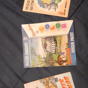 May include: Three vintage Milton Bradley art kits: "Modeling with Clay" featuring a rabbit, "Adventures in Color" with a farm scene, and "Magic with Water Color." The kits have colorful illustrations and text.