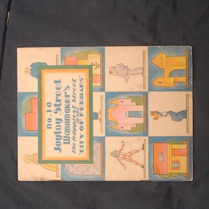 May include: A vintage illustrated book cover with the title "Joytoy Street Wanamaker's the happiest street in the "CITY OF PERHAPS" "
