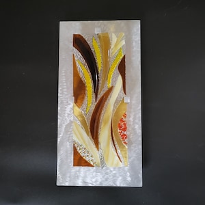 Fused stained glass mounted on 1.5 in standoffs above brushed aluminum backplate. Fused glass art is shades of brown with orange, shimmering gold dichroic large accent sweeps and small dichroic balls.