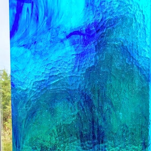 May include: Abstract stained glass panel with a textured surface. The panel features a gradient of blues and greens, creating a watery effect. The colors range from deep indigo to light turquoise.
