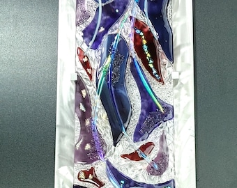 May include: Abstract wall art featuring a silver metal frame with a glass panel. The glass panel is filled with a mosaic of purple, red, and blue glass pieces. The glass pieces are arranged in a random pattern, creating a modern and abstract design.