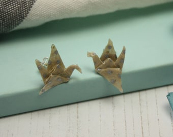 May include: A pair of origami crane earrings made from patterned paper with silver accents. The cranes are folded in a traditional style and have a delicate, feminine look.