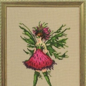 Puede incluir: Obra de arte de punto de cruz de un hada en un marco dorado. El hada tiene un vestido rosa, medias verdes y alas verdes con forma de hojas. La cabeza del hada está adornada con una corona de flores rosas y hojas verdes. El fondo es beige neutro.