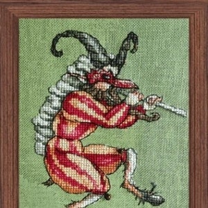 May include: A cross-stitch pattern of a whimsical, red and white striped jester with a black hat and a mask, playing a flute. The jester has long, pointed shoes and is standing on a green background.