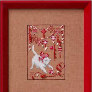May include: White cat playing with red and white ornaments hanging from a string. The ornaments are decorated with a red and white checkered pattern. The cat is wearing a red bow.