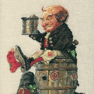 May include: Cross-stitch depiction of a jovial leprechaun seated on a wooden barrel, holding a tankard. The leprechaun wears a black coat, red vest, and green and red socks. A black hat with a shamrock sits nearby. The barrel has a rose design.