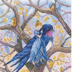 Op de afbeelding: Een kruissteekpatroon met een blauwe vogel waarop een meisje rijdt. De vogel zit op een tak van een boom met gele bladeren. De achtergrond is een lichtblauwe lucht met witte wolken.