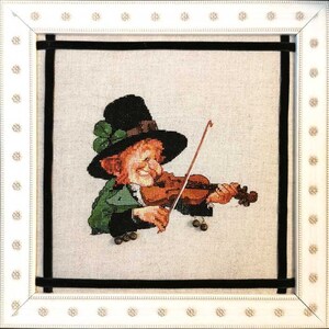 May include: A cross-stitch embroidery of a leprechaun wearing a green hat and playing a violin. The leprechaun is smiling and has a green shamrock on his hat.