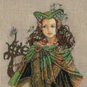May include: Cross-stitch artwork of a woman with pointed ears, wearing a green and brown cloak and a leafy headdress. Her skin is fair, with blue eyes and red hair. A decorative element with a butterfly is on the left.