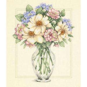 Può includere: Natura morta floreale con un vaso di vetro trasparente pieno di un bouquet di fiori. Il bouquet comprende grandi fiori color crema con centri marroni, fiori rosa e blu e foglie verdi. Lo sfondo è beige chiaro.