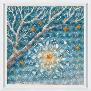 Pu&ograve; includere: Un ricamo a punto croce con un fiocco di neve bianco con un centro giallo, un ramo di albero bianco con foglie arancioni e uno sfondo blu con piccole stelle gialle.