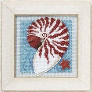 May include: A framed cross-stitch embroidery featuring a nautilus shell with red and white striped patterns on a light blue background with swirling line details. A small, red, five-pointed star-shaped button is attached to the lower right corner.