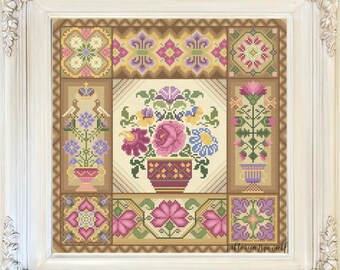 May include: Cross-stitch floral design in a white ornate frame. The artwork features a central vase of flowers surrounded by patterned panels in shades of pink, purple, yellow, and green. The frame has decorative corner accents.