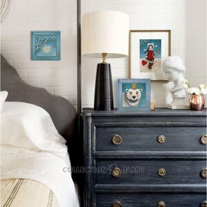 Pu&ograve; includere: Tre illustrazioni incorniciate su una cassettiera blu scuro con un letto bianco sullo sfondo. Le illustrazioni sono di una scena invernale con una stella, una ragazza con un cappotto rosso e un orso polare con una corona.