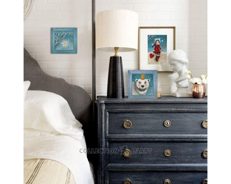 Pu&ograve; includere: Tre illustrazioni incorniciate su una cassettiera blu scuro con un letto bianco sullo sfondo. Le illustrazioni sono di una scena invernale con una stella, una ragazza con un cappotto rosso e un orso polare con una corona.