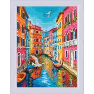 May include: A colorful cross-stitch of a Venetian canal scene. Buildings in shades of orange, pink, yellow, and blue line the waterway. Boats and a seagull are visible on the water, reflecting the vibrant colors of the buildings and sky.