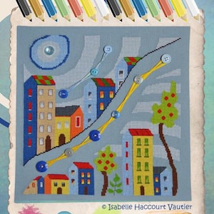May include: A cross-stitch pattern of a whimsical cityscape with colorful buildings, trees, and a winding road. The design features a blue sky with white clouds and a yellow path with blue buttons.