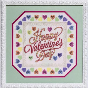 Puede incluir: Un bordado de punto de cruz blanco con un marco octogonal rosa. El centro del bordado presenta el texto "Happy Valentine's Day" en letras rojas y amarillas. El borde del bordado está decorado con corazones coloridos con varios mensajes, como "Say Yes", "Pick Me", "Love You" y "Hug Me".