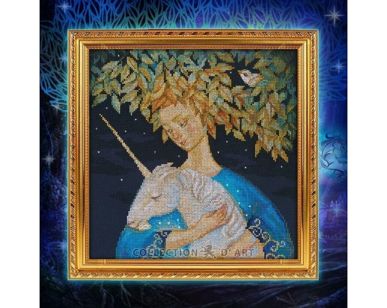 May include: Cross-stitch artwork in a gold frame depicts a woman with a leafy crown embracing a unicorn. The woman wears a blue gown, and the background is a dark blue night sky with stars. The artwork is labeled "COLLECTION D' ART".