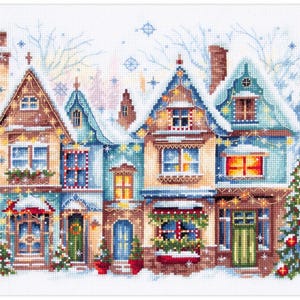 Può includere: Un modello a punto croce raffigurante una fila di case innevate, decorate con luci e ghirlande natalizie. Le case sono nei toni del blu, marrone e verde, con alberi di Natale. Una scena invernale festosa.
