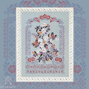Könnte beinhalten: Kreuzstich-Stickerei mit einem Blumendesign mit zwei Vögeln, die auf Zweigen mit weißen Blüten sitzen. Das Kunstwerk ist in einem weißen Rahmen eingefasst und vor einem hellblauen Hintergrund mit dekorativen Mustern platziert. Die Farbpalette umfasst Rot, Lila und Orange.