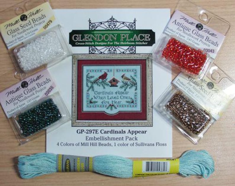 May include: A Glendon Place Cardinals Appear cross-stitch pattern sheet with four Mill Hill glass seed bead packets in white, red, dark green, and bronze, plus a skein of light blue Sullivans embroidery floss for needlework projects.