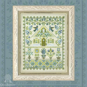 Könnte beinhalten: Gerahmtes Kreuzstich-Kunstwerk mit einem detaillierten Hausdesign mit grünem Dach, blauen Akzenten sowie Blumen- und Vogelmotiven. Das Kunstwerk befindet sich in einem weißen, verzierten Rahmen vor einem blau gemusterten Hintergrund. Das OwlForest-Logo ist sichtbar.