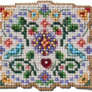 Puede incluir: Un diseño de punto de cruz blanco con un patrón floral, dos pájaros azules y un corazón rojo en el centro. El diseño está rodeado por un borde marrón.