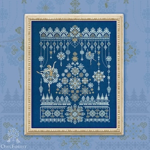 Könnte beinhalten: Gerahmtes Kreuzstich-Kunstwerk mit Winterballett-Thema. Das Design umfasst Schneeflocken, Ballerinas und dekorative Bordüren in Weiß-, Gold- und Blautönen. Der Rahmen ist hellbeige und unterstreicht die Details des Kunstwerks.