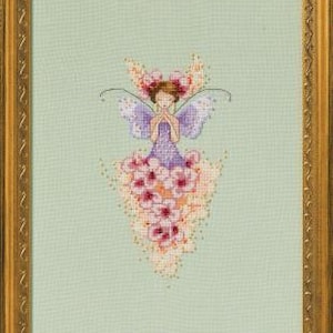 May include: Cross-stitch artwork of a fairy in a gold frame. The fairy has purple wings and a dress made of pink flowers. The background is a light green color.