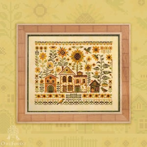 Könnte beinhalten: Kreuzstich-Kunstwerk mit einer detaillierten Dorfszene mit Häusern, Sonnenblumen und Vögeln. Das Kunstwerk ist in einem hellbraunen Holzrahmen gerahmt. Die Farbpalette umfasst Gelb-, Grün- und Brauntöne.