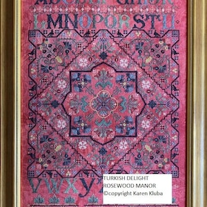 May include: Framed cross-stitch sampler with a detailed geometric design in shades of red, blue, and green. The design includes the alphabet and floral motifs. The text "TURKISH DELIGHT ROSEWOOD MANOR ©copyright Karen Kluba" is visible.