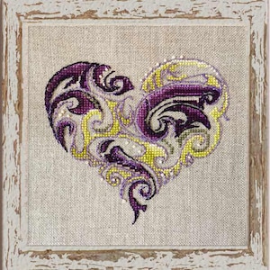 May include: A purple and yellow embroidered heart with intricate floral designs. The heart is framed in a distressed white wood frame.