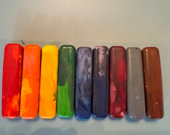 May include: A set of ten crayons in various colors, including red, orange, yellow, green, blue, purple, brown, and gray. The crayons are arranged in a row from left to right.