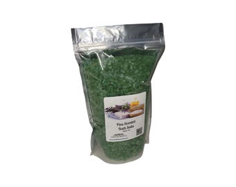 Może przedstawiać: Przezroczysta, zamykana torebka wypełniona zielonymi solami do kąpieli. Torebka ma etykietę z napisem "Pine Scented Bath Salts" i obrazem lawendy, mydła i ręczników. Sole do kąpieli są grube i ziarniste.